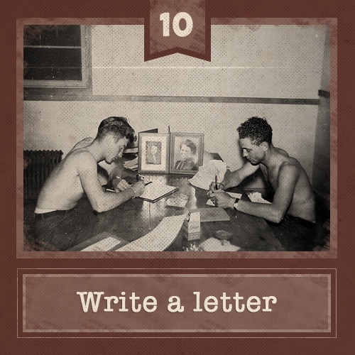 Vintage men sitting at table shirtless writing letters.