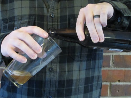 Man pouring beer into pint glass.