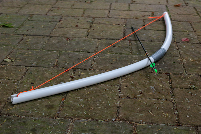 A white bow with a red arrow attached to it for archery practice.
