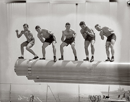 A group of men posing on top of a ship during a military fighter drill.