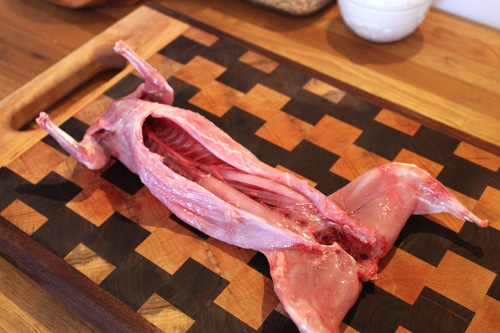 Washed rabbit body on cutting board is being displayed.
