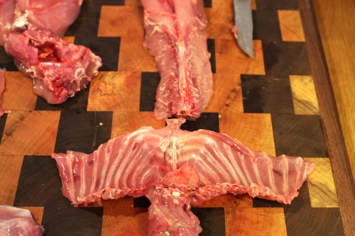 Man cutting off the ribs and neck of rabbit.