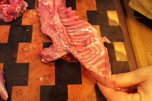 Man cutting off the pelvis part of rabbit.