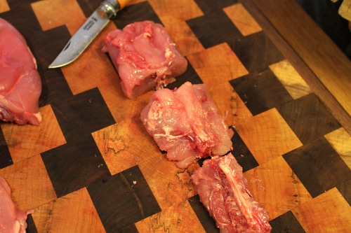 Man cutting off the spine of rabbit with knife.
