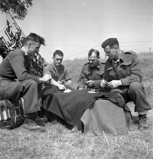 A group of manly men sitting on a blanket playing cribbage.