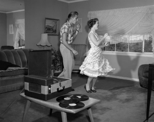 1950s Laughing Teenage Couple Dancing To The Phonograph Playing 78 Rpm Records In Living Room Vintage lovers dancing in the longue.
