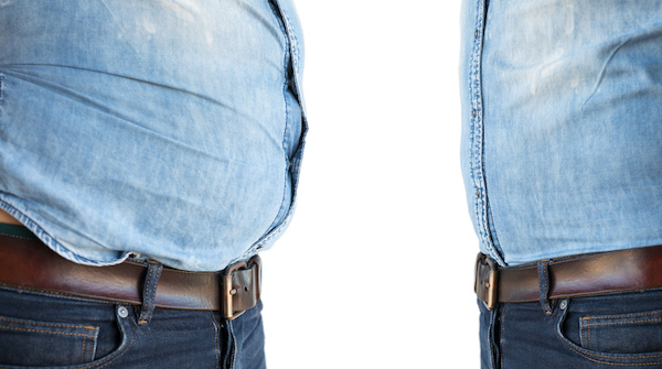 A man wearing a denim shirt with a belt walks confidently down the street.