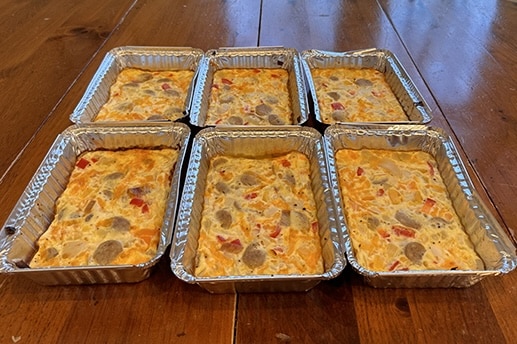 A stack of cheap aluminum pans with high-protein breakfast casseroles in them.