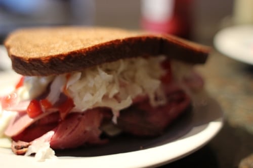 A sandwich with meat and coleslaw, part of the AoM Month of Sandwiches event, served on a plate.