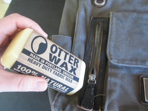 Man applying wax bar on bag zip.
