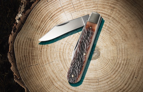 A handy knife is resting on a piece of wood.