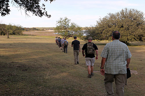 Men walking in a row on the ground.