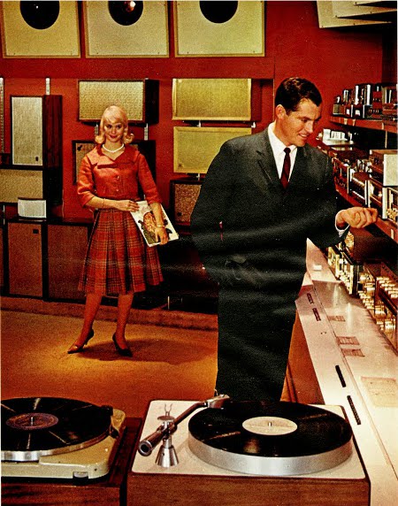 An American bachelor and his companion standing next to a record player from the 20th and 21st century.