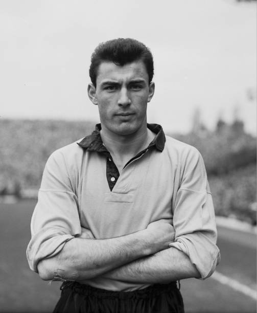 A quiet man with his arms crossed in a black and white photo exudes power.