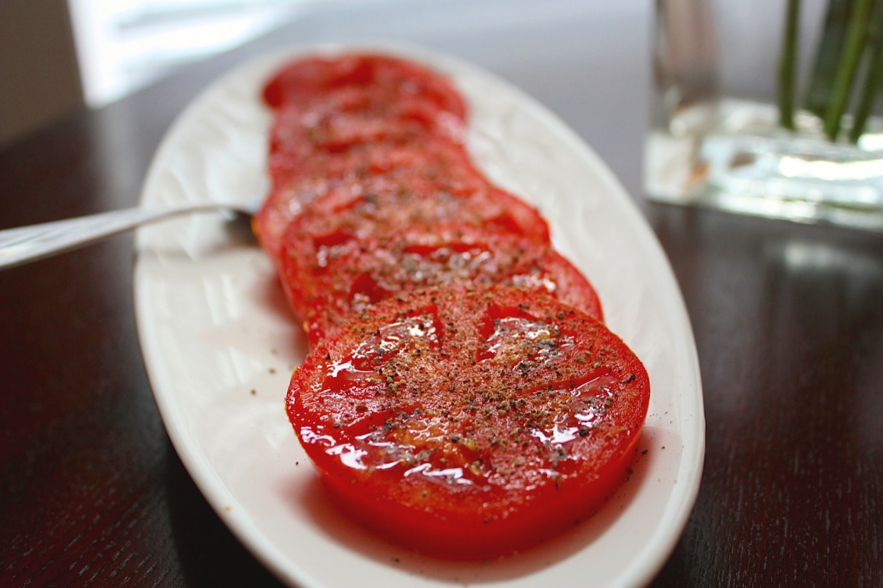 Quick sliced tomatoes on a white plate.