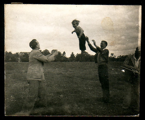 Vintage men tossing young boy between them.