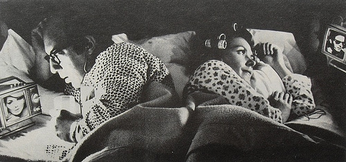 Couple lying on bed while watching tv.