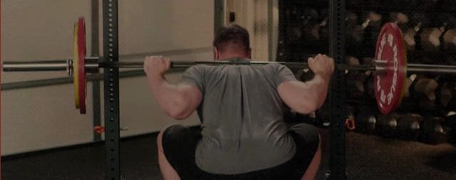 A man troubleshooting his squat form in the gym.