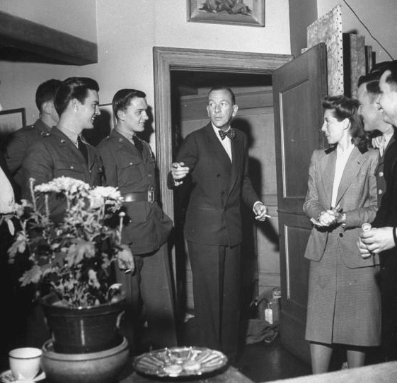 Man leaving a room Formally dressed vintage man leaving the room while pointing something along with people.