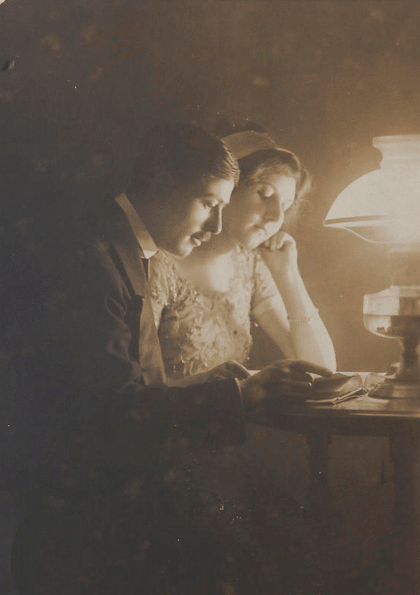 Vintage 1800's couple reading together under a lamp.