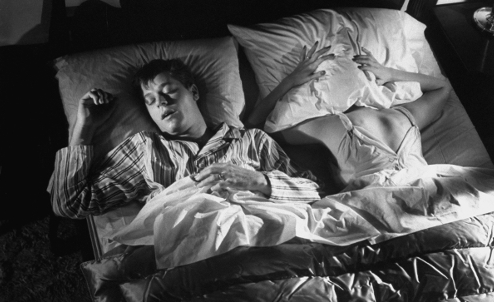 A man and a woman sleeping in bed, with the man snoring loudly.